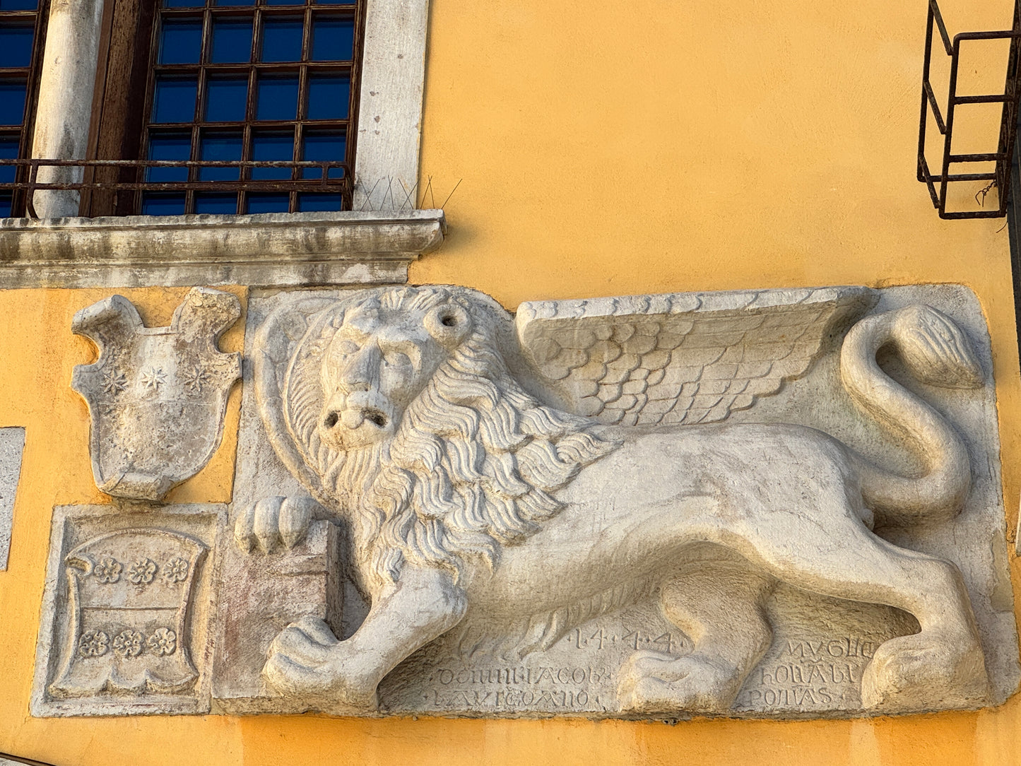 Markuslöwe auf dem Rathaus in Muggia mit geschlossene Buch auf einer gelben Fassade