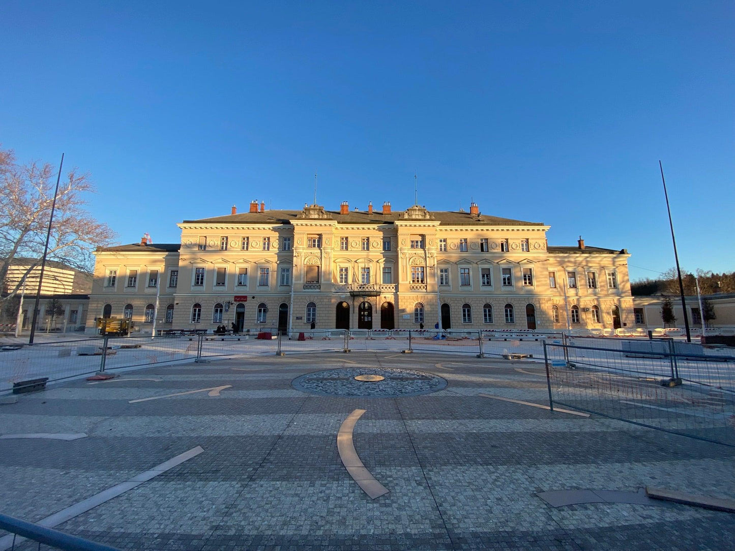 Piazza della Transalpina in Görz in der Abendsonne mit dem sonnenbeschienen Bahnhof im Hintergrund