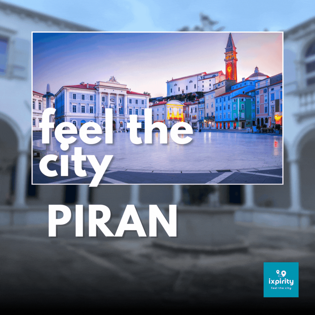 Häuser auf dem Tartina Platz in Piran mit Bueleuchtung und Blick auf die Kirche sowie dem Schriftzug feel the city Piran. Auf der linken Seite steigen rote Bubbles mit weißen Herzen nach oben
