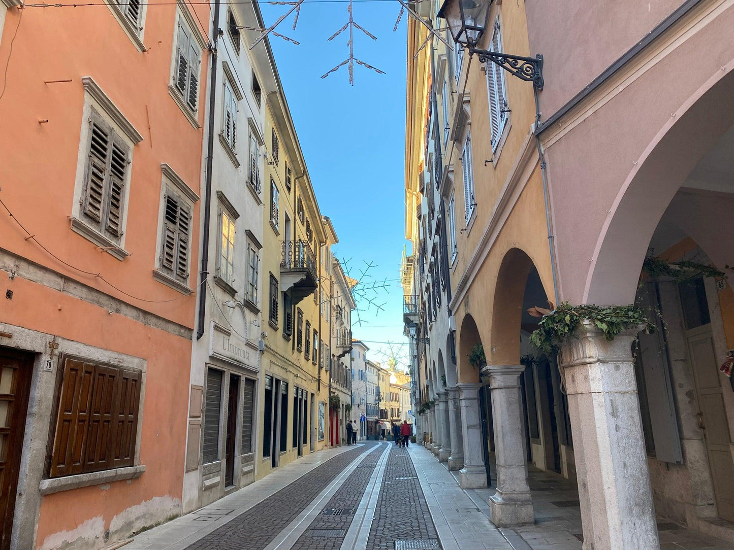 Via Rastello in Görz mit bunten Häusern und einem Arkadengang auf der rechten Seite