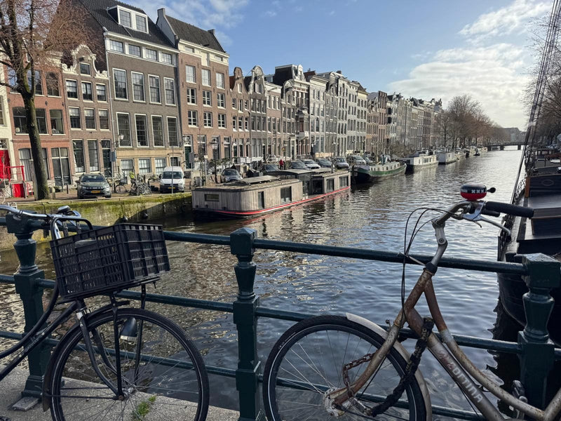Amsterdamer Gracht mit geparkten Fahrrädern am Brückengeländer und Grachtenhäusern im Hintergrund
