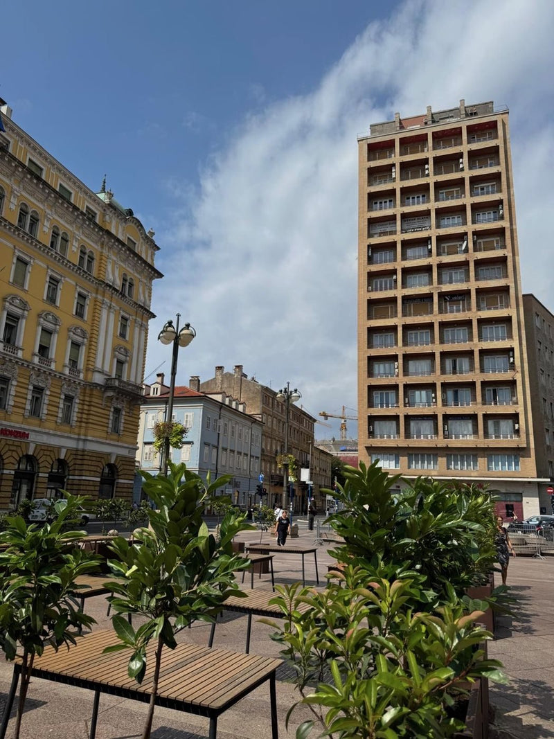 Der Jadranski trg in Rijeka mit dem Wolkenkratzer Neboder und den Fontänen auf dem Platz.