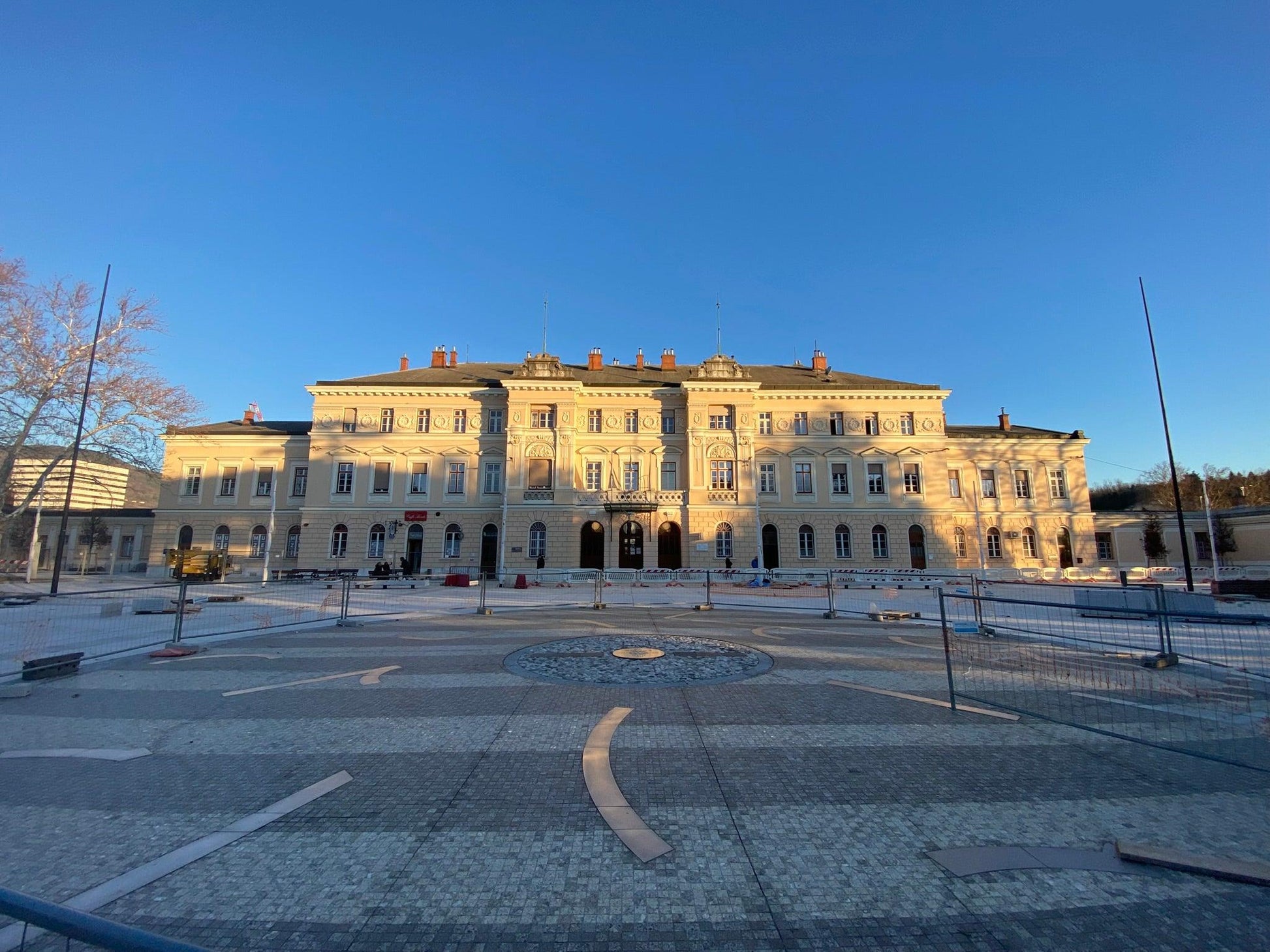 Piazza della Transalpina in Görz in der Abendsonne mit dem sonnenbeschienen Bahnhof im Hintergrund 