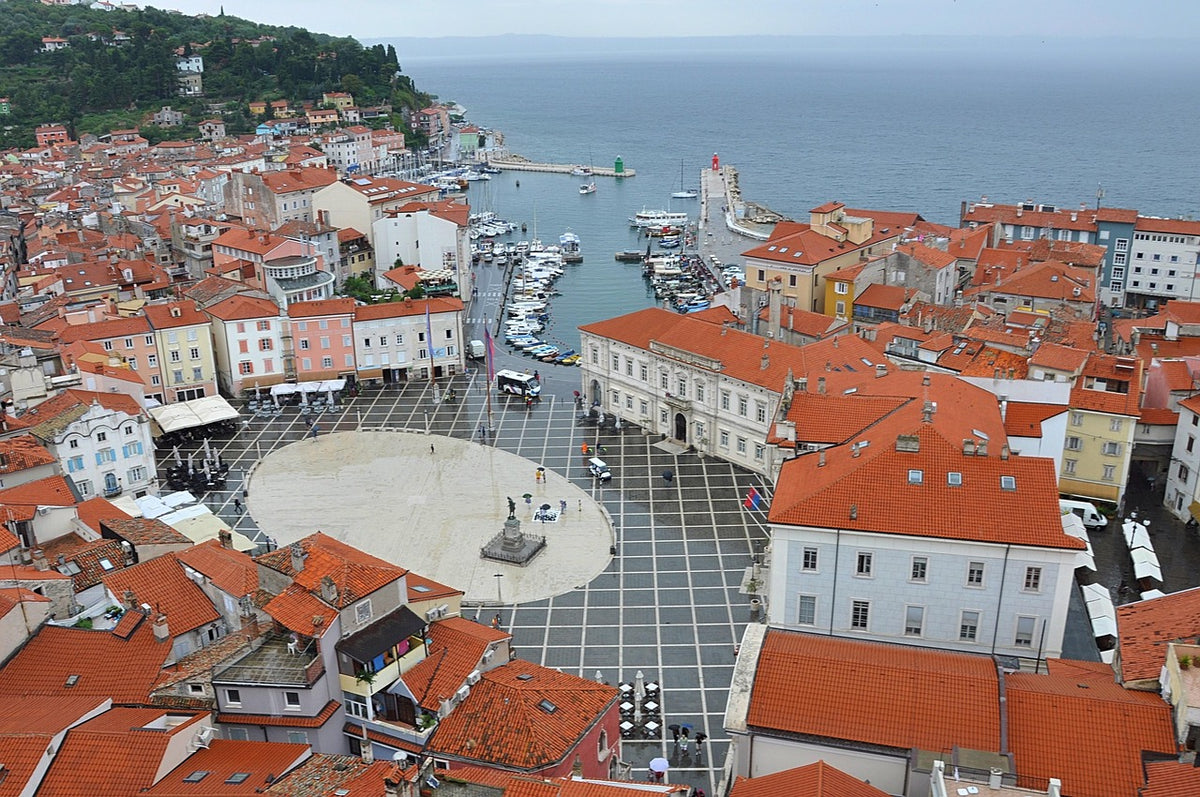 Blick von oben auf den Tartini-Platz in Piran mit roten Dächern, Hafen und Meer
