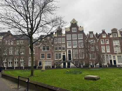 Der begrünte Innenhof des Begijnhof in Amsterdam mit historischen Wohnhäusern rund um eine Rasenfläche.