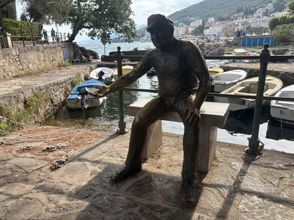 Die Bronzefigur des Barkajol, des Bootsmanns von Opatija, auf der Mole des kleinen Hafens Portić.