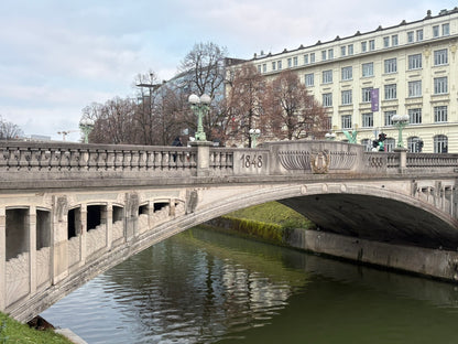 Tageslichtaufnahme der ikonischen Drachenbrücke (Zmajski most) in Ljubljana, mit ihren markanten kupfernen Drachenstatuen auf den Brückenpfeilern und der Jugendstil-Architektur.