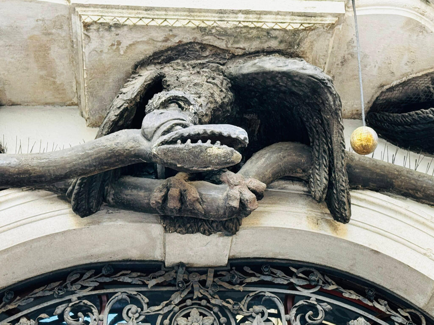 Stone dragon relief with a golden orb on a house facade in Trieste