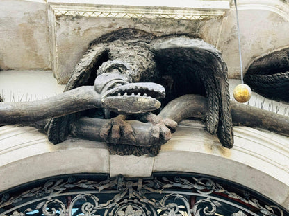 Stone dragon relief with a golden orb on a house facade in Trieste