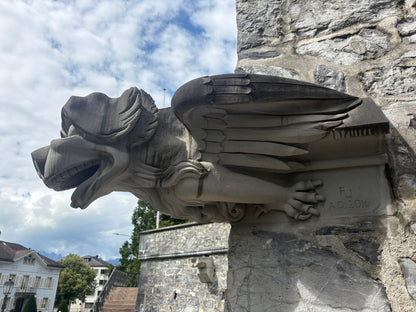 Stone winged creature sculpture in front of a rock face in Vaduz