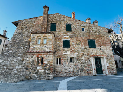 Casa in mattoni a tre piani con persiane verdi: la Casa della Musica a Grado