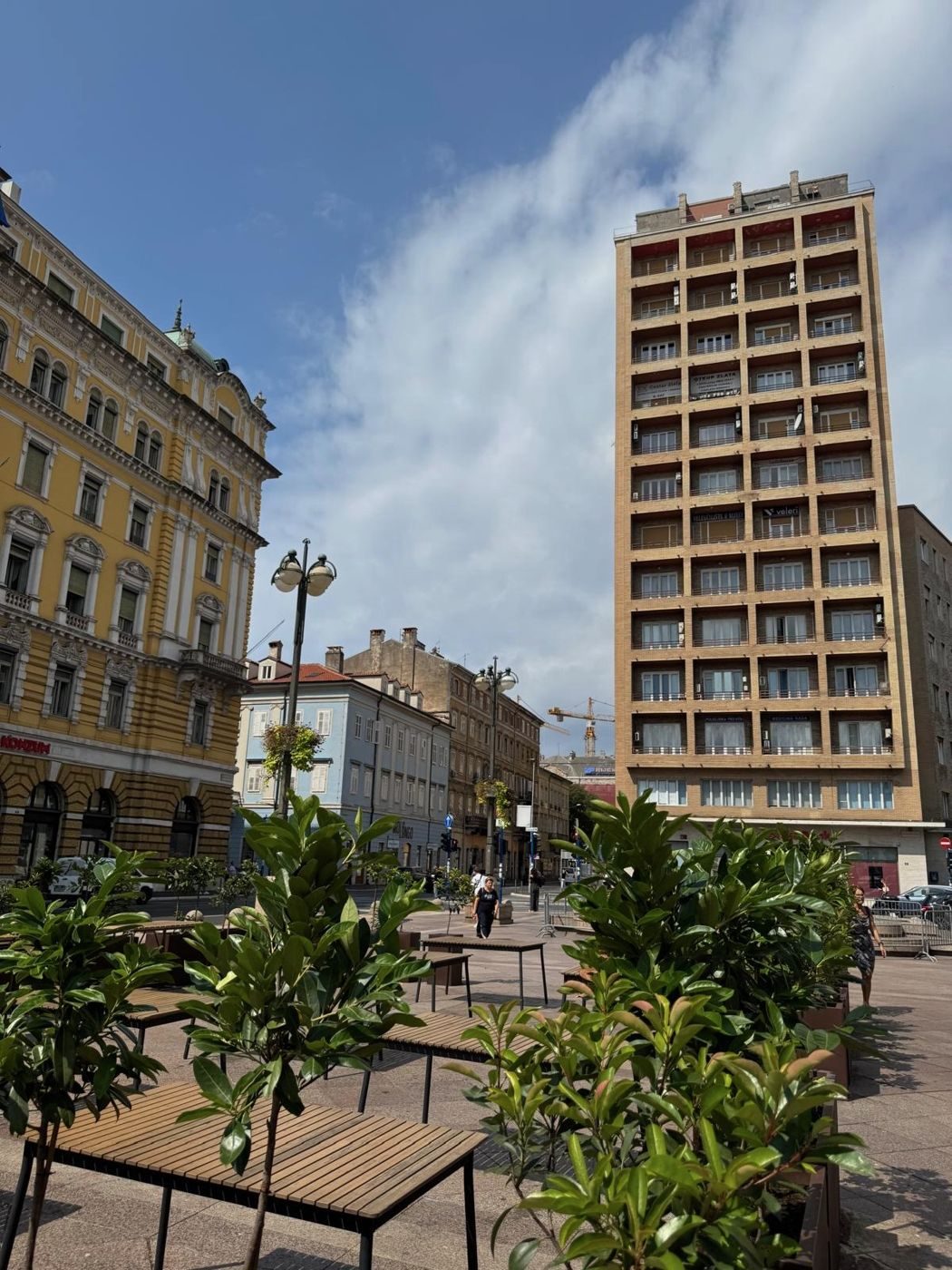 Der Jadranski trg in Rijeka mit dem Wolkenkratzer Neboder und den Fontänen auf dem Platz.