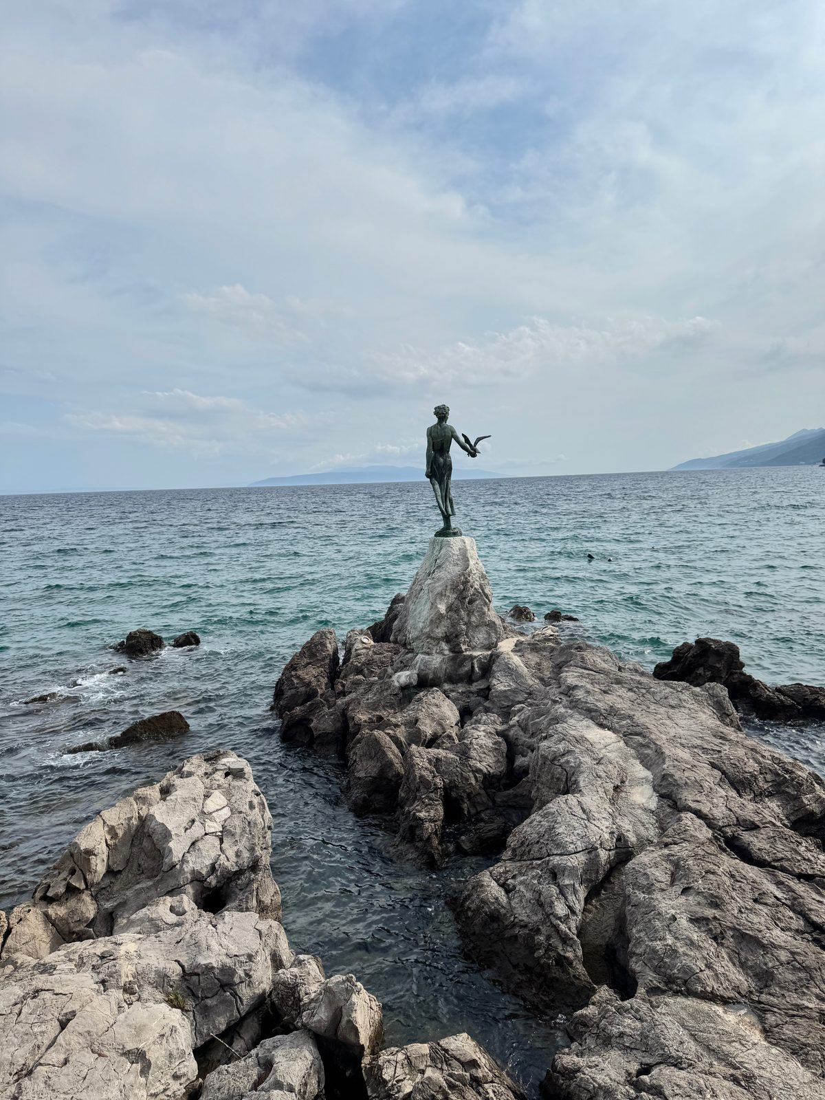 Die Bronzestatue Djevojka s galebom, das Mädchen mit der Möwe, auf ihrem Felsen im Meer vor Opatija.