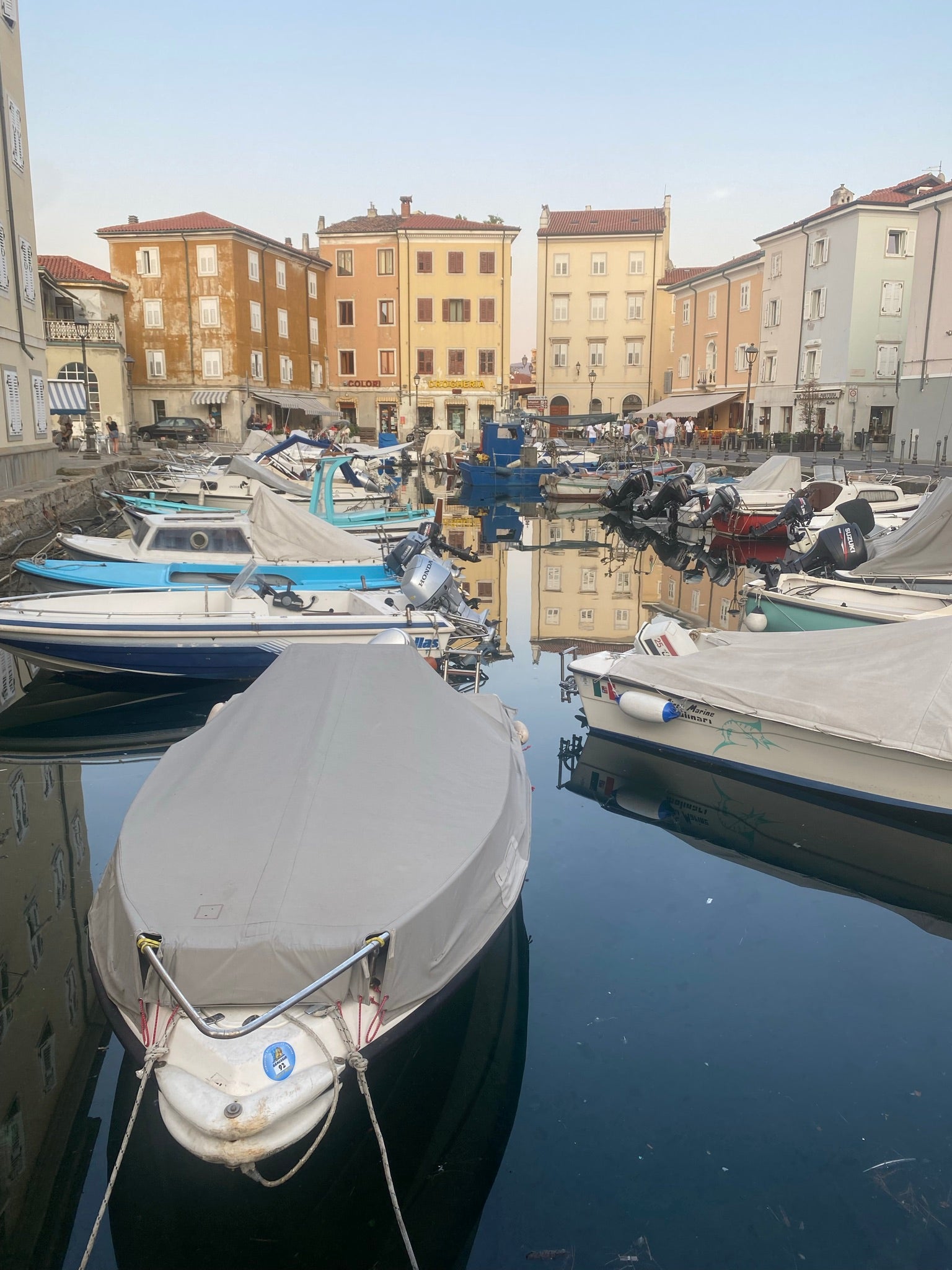 Mandracchio harbour in Muggia with colourful boats and houses in the evening sun