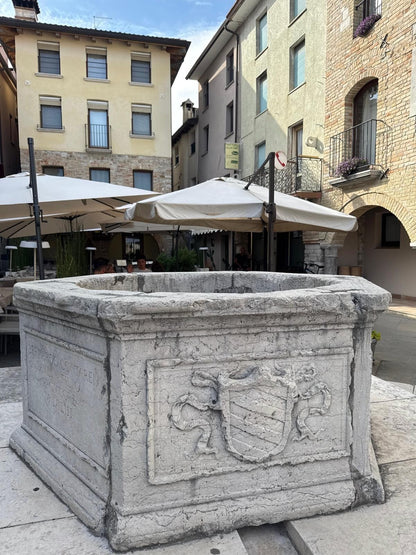 Steinbrunnen mit Wappen auf der Piazza von Marano Lagunare – Rätselstation der Tour