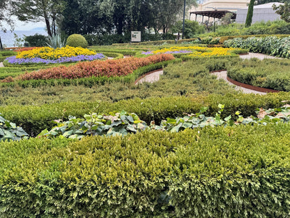 Blumenbeete und geschnittene Hecken im Park Angiolina in Opatija, dahinter die alte Villa im Grünen.