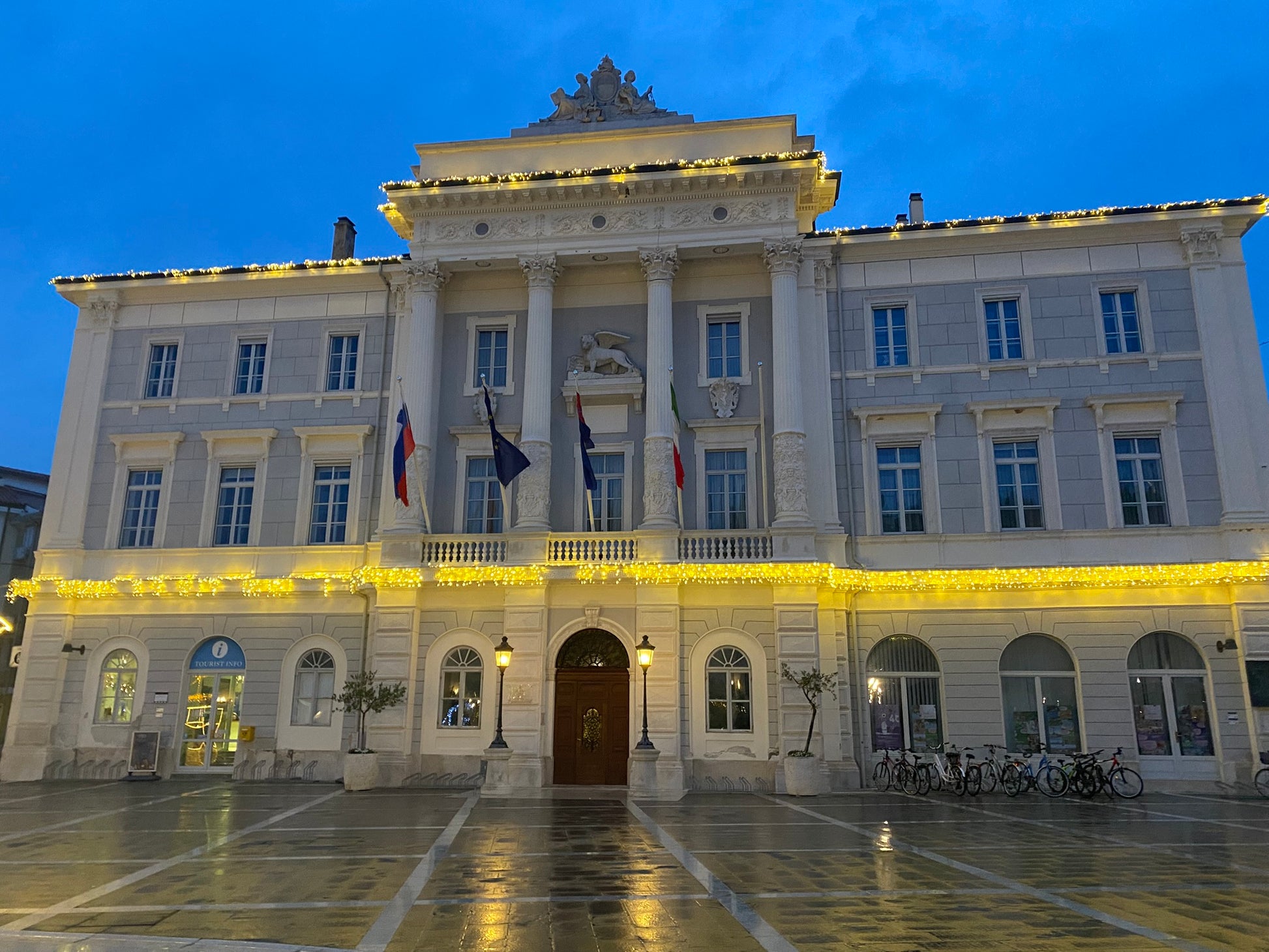 Il municipio di Pirano illuminato di sera con le bandiere slovena, italiana ed europea