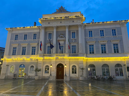 Il municipio di Pirano illuminato di sera con le bandiere slovena, italiana ed europea