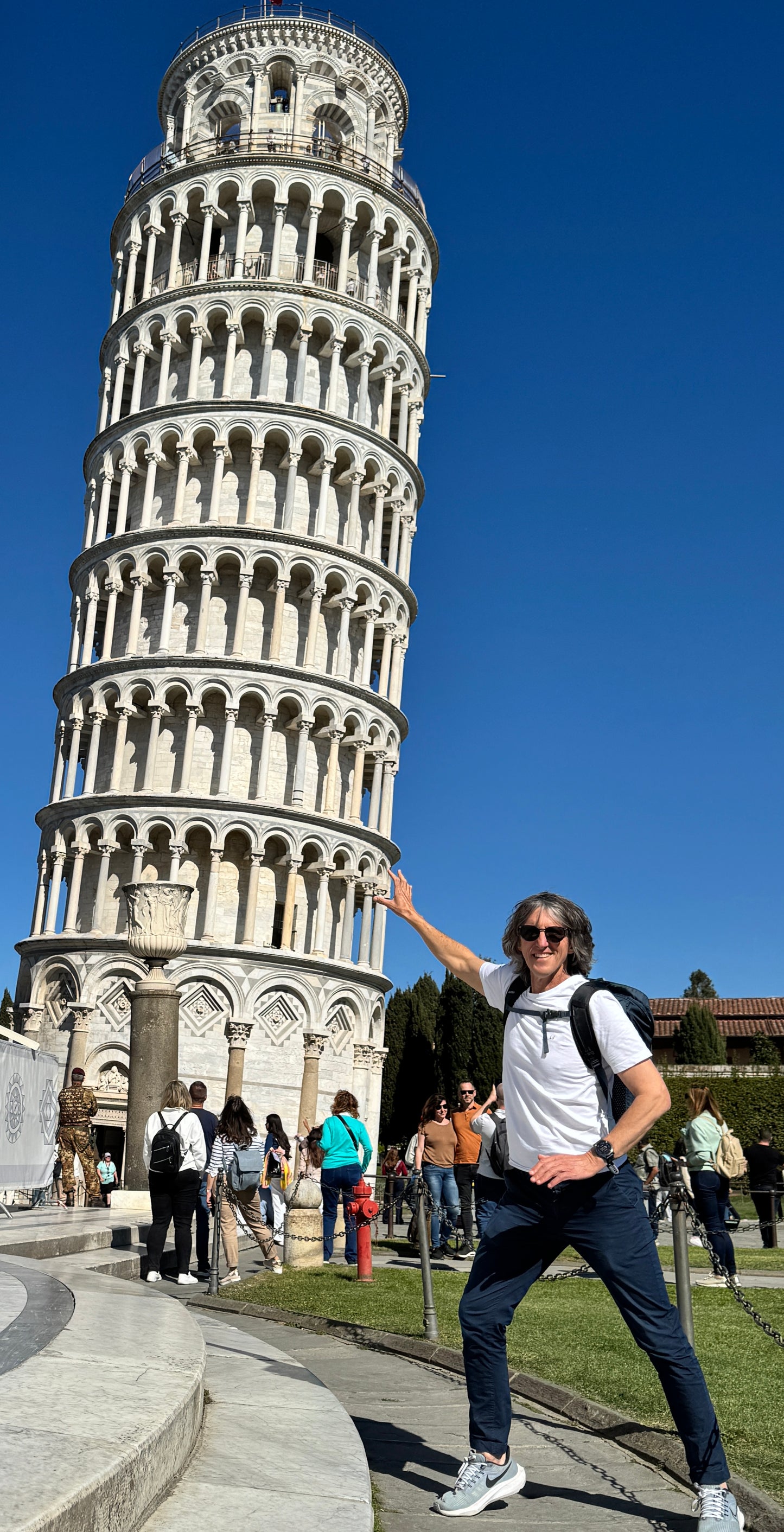 Un visitatore in posa davanti alla Torre Pendente in Piazza dei Miracoli a Pisa