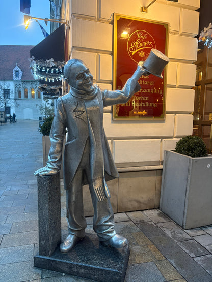 Statua di Schöner Náci con cilindro davanti al Café Mayer nel centro di Bratislava